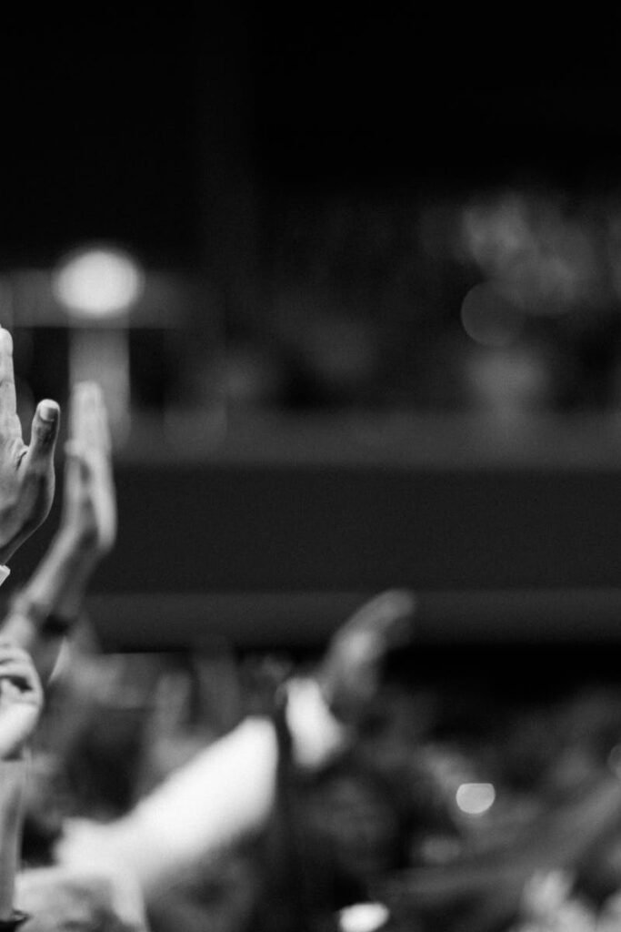 Black and white image of audience with hands raised, capturing concert energy.